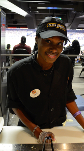 A Cajun Corner crew member smiling behind the concession counter