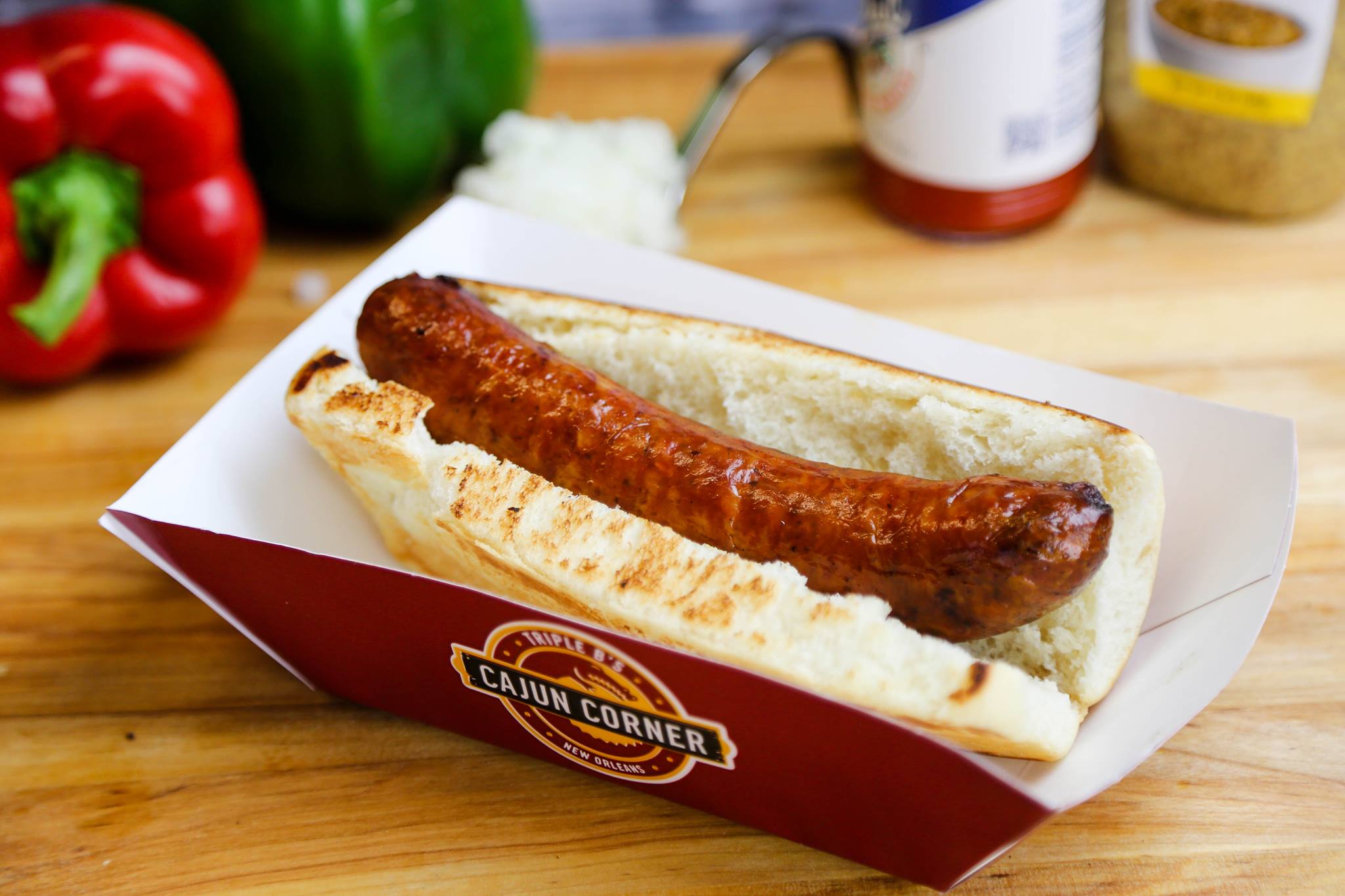 A freshly grilled alligator sausage poboy in a toasted bun, served in a Cajun Corner tray
